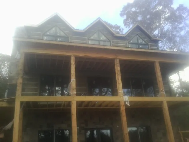 Dormers and porch framing on a large log home under construction — Roof Coating work by our crew in Huntsville